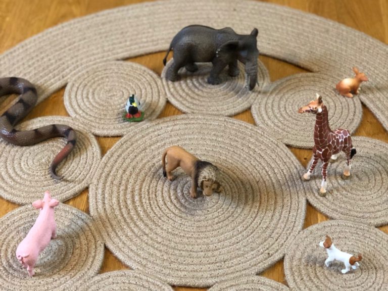 Eine Ansammlung von Tierfiguren auf einem kreisförmigen Juteteppich.