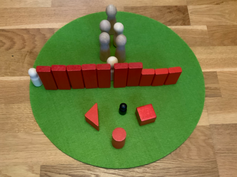 Bunte Spielfiguren und Formen auf einem grünen Untergrund angeordnet.
